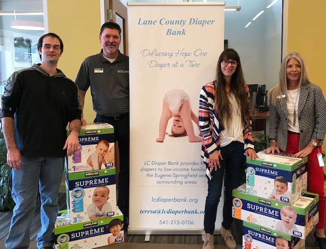 Downtown Eugene branch staff with Lane County Diaper Bank employees and boxes of diapers.